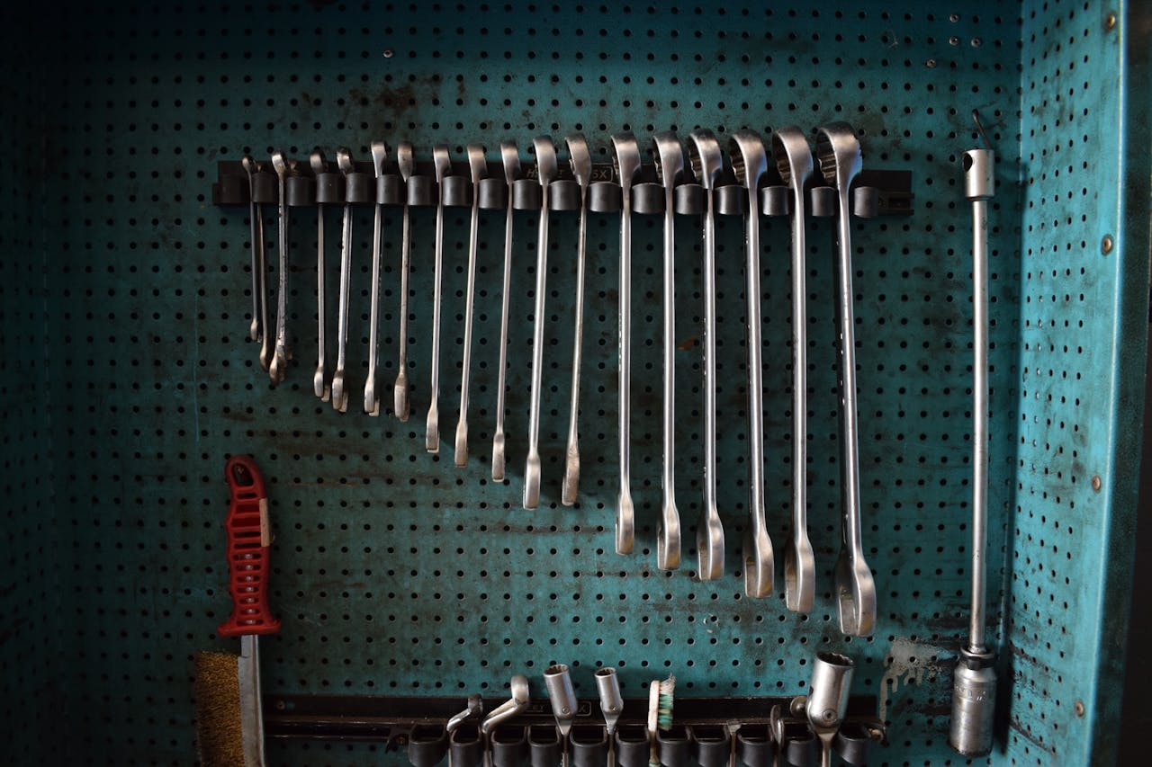A neatly arranged set of wrenches on a perforated tool board in a workshop setting.