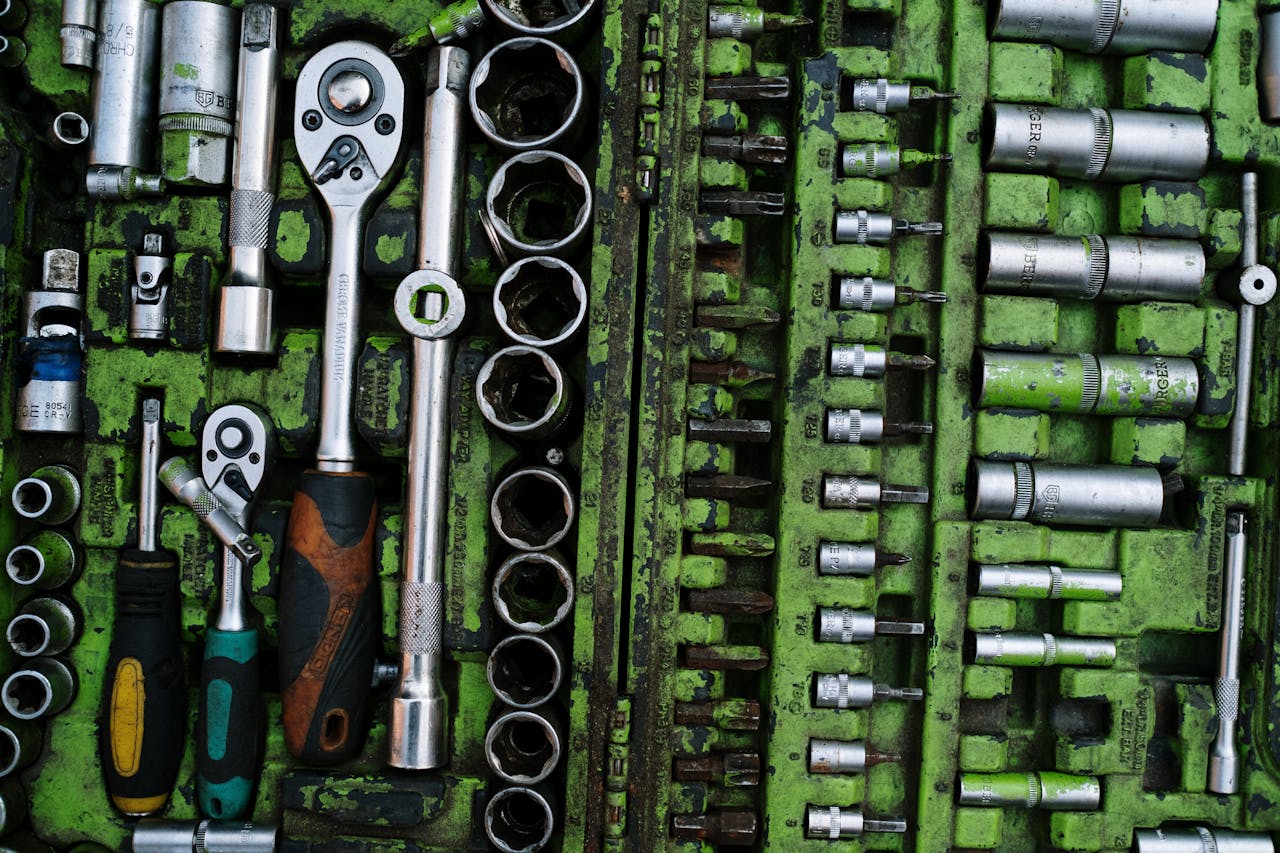 A well-organized set of metal tools in a green toolbox with ratchets and screwdrivers.
